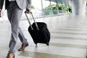 businessman walking with a wheeled suitcase