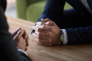 two sets of clasped hands on a desk