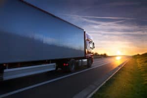 truck driving a road at sunset